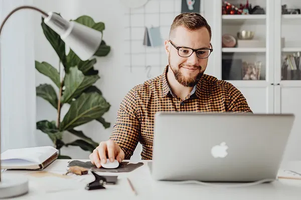 Man with glasses using laptop on desk