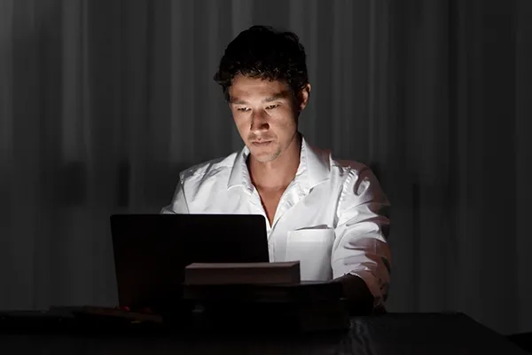 Man looking down at laptop in a dark room