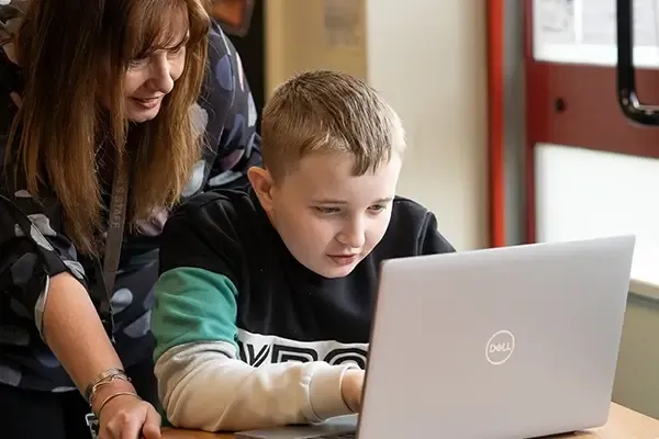 Teacher helping a student on his laptop